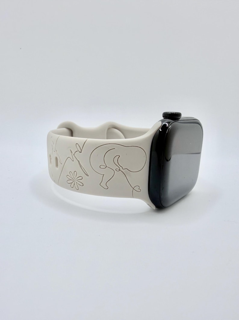 May include: A light gray silicone watch band attached to a black smartwatch. The band features a continuous line drawing design depicting a fetus, a flower, and a heartbeat rhythm line engraved into the surface of the flexible material.