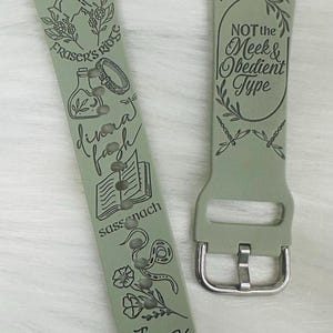 Może przedstawiać: Zielony skórzany pasek do zegarka z grawerowanymi wzorami i tekstem, w tym "Est. 1767", "Fraser's Ridge", "sassenach", "divina fasch", "NOT the Meek & Obedient Type" oraz "Jesus H. Roosevelt Christ!"