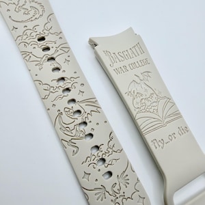 May include: A light beige silicone watch band featuring engraved dragon motifs, stars, and clouds. One section displays the text "BASGIATH WAR COLLEGE" above an open book illustration and the phrase "fly...or die" in a stylized serif font.