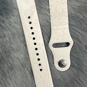 May include: Cream-coloured watch strap with etched designs. Features a lightning bolt, a broom, stars, and the word "always". Includes images of a castle, an open book, and the number 9 3/4.