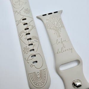 May include: A light beige silicone watch band featuring laser-engraved designs. One strap displays a fetus, baby footprints, a rainbow, and the text "oh baby". The other strap shows a bouquet of flowers and the text "labor & delivery".