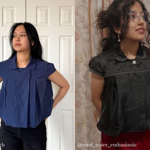 May include: Two short-sleeved tops. One is navy blue with a pleated front and a collar. The other is dark gray with a white star on the collar. Both tops have a similar design and are worn by individuals.