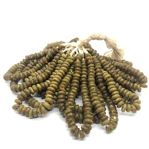 May include: A strand of green glass beads with a speckled finish. The beads are round and have a slightly irregular shape. The strand is tied together with a white string.