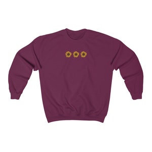 May include: A maroon sweatshirt with three embroidered yellow sunflowers on the front.