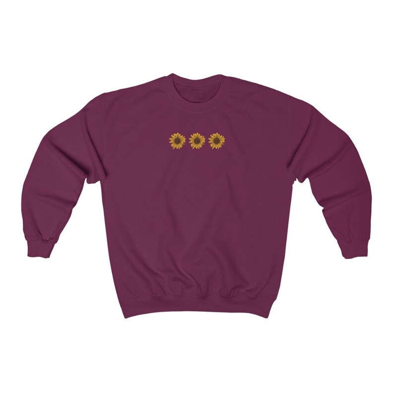 May include: A maroon sweatshirt with three embroidered yellow sunflowers on the front.