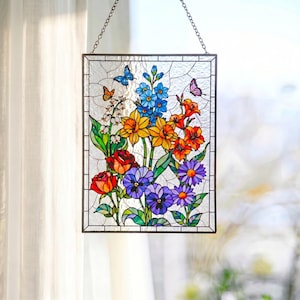 May include: A rectangular stained glass suncatcher featuring a vibrant floral arrangement with red roses, yellow daffodils, blue delphiniums, purple pansies, and orange lilies, accented by two small butterflies and white lily of the valley.