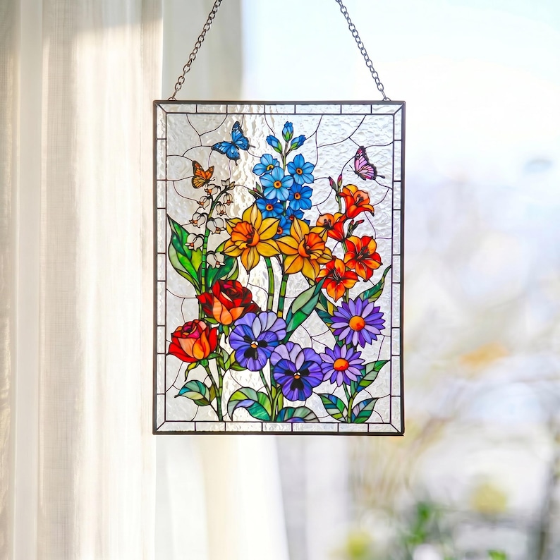 May include: A rectangular stained glass suncatcher featuring a vibrant floral arrangement with red roses, yellow daffodils, blue delphiniums, purple pansies, and orange lilies, accented by two small butterflies and white lily of the valley.