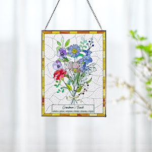 May include: Stained glass panel featuring a colorful floral bouquet with red, purple, blue, and white flowers. The panel has a yellow and orange border and is suspended by a chain. Text at the bottom reads "Grandma's Bunch".