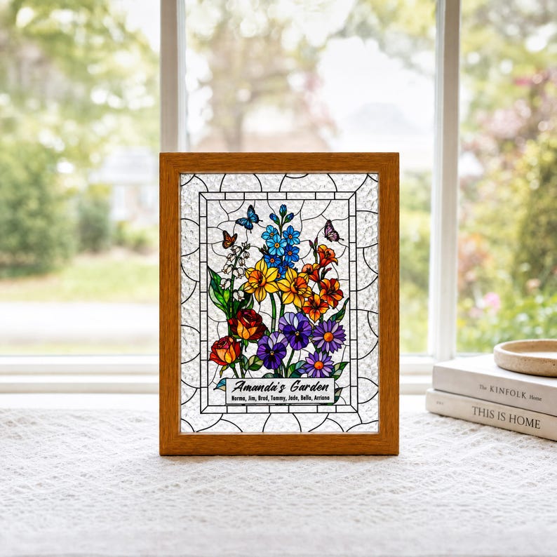 May include: A rectangular stained glass panel in a wooden frame featuring a colorful floral arrangement with blue, yellow, orange, red, and purple flowers and butterflies. The text reads Amanda's Garden with names listed below in black.