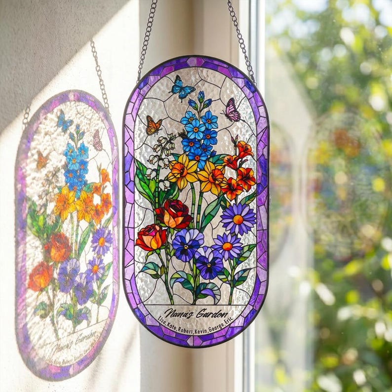 May include: An oval stained glass suncatcher featuring a floral arrangement with blue, yellow, orange, red, and purple flowers and butterflies. The text "Nana's Garden" and names "Lisa, Kate, Robert, Kevin, George, Eric" are printed at the bottom.