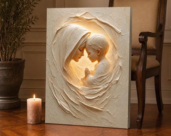 May include: A rectangular wall art piece featuring a cream-colored, three-dimensional relief sculpture of a figure in a hooded cloak cradling a small child with hands pressed together in prayer, illuminated from behind with a warm, soft glow.