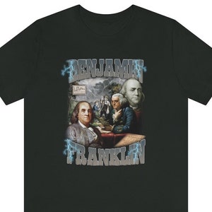 Puede incluir: Camiseta negra con un estampado gráfico de Benjamin Franklin con rayos y el texto "Benjamin Franklin".