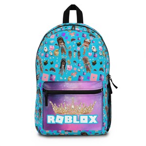 Könnte beinhalten: Ein blauer Rucksack mit einem Galaxie-Druck und einer goldenen Krone mit dem Wort "ROBLOX" in rosa Buchstaben. Der Rucksack ist mit einem Muster aus Comicfiguren und Objekten aus dem Online-Spiel Roblox bedeckt.
