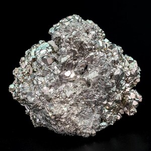 Può includere: Un gruppo di pirite, nota anche come oro degli stolti, su sfondo nero. Il minerale metallico ha una struttura cristallina con un aspetto riflettente, simile all'argento. La formazione di pirite ha una forma irregolare.