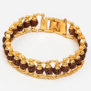 May include: A gold bracelet featuring brown beads. The bracelet is made of a chain with small gold accents. The beads are round and have a rough texture.
