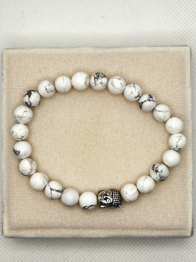 May include: White Howlite beaded bracelet with a silver Buddha charm.