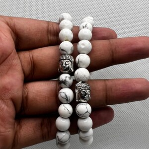 May include: Two white marble beaded bracelets with silver Buddha head charms.