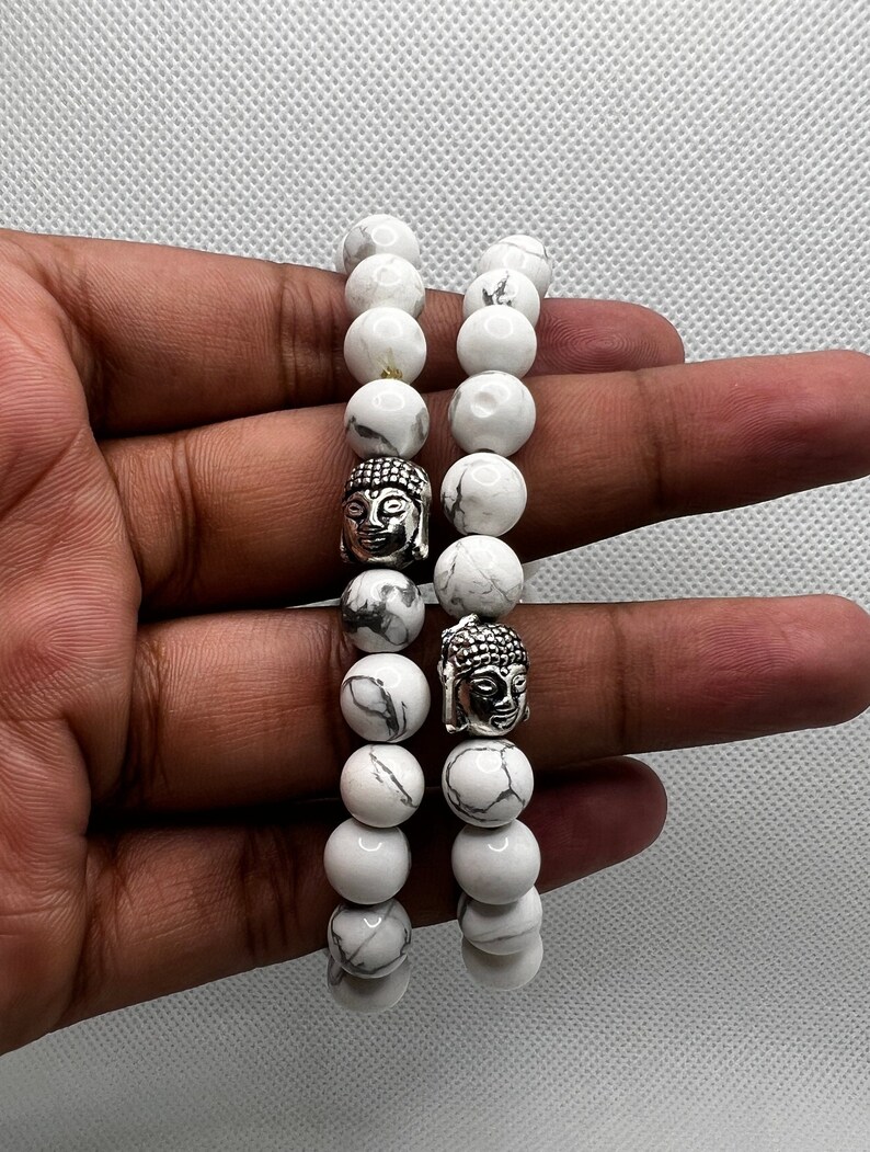 May include: Two white marble beaded bracelets with silver Buddha head charms.