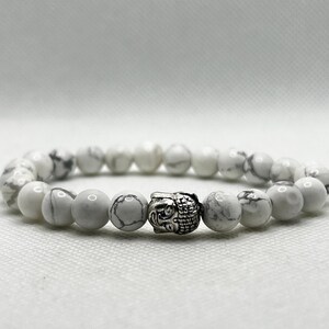 May include: White Howlite beaded bracelet with a silver Buddha head charm.