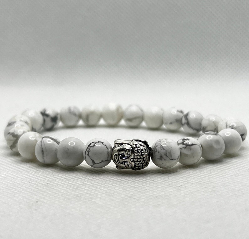 May include: White Howlite beaded bracelet with a silver Buddha head charm.