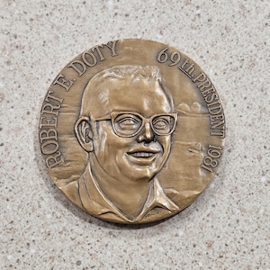 May include: A bronze medal with a portrait of Robert E. Doty, the 69th president in 1981.