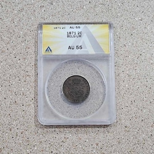 May include: A silver coin from 1871, graded AU 55, in a clear plastic coin holder with a yellow label that reads "1871 2C Belgium AU 55".