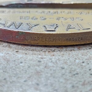 May include: Close-up of a bronze medal with the text "William E.  1865-1945 Company" and a crown. The bottom of the medal reads "Medallic Art Co. N.Y. Bronze."