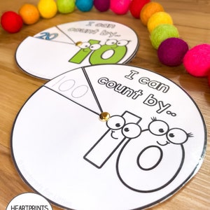 May include: Two colorful printable spinners with the text "I can count by..." and a large number 10 with eyes and a smile. The spinners are divided into two sections, one with the number 10 and the other with the numbers 20 and 100.