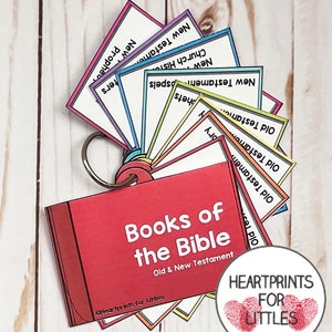 May include: A red book with the title "Books of the Bible" and the subtitle "Old & New Testament". The book is open to reveal a set of colorful cards with the names of the books of the Bible, including "Old Testament", "New Testament", "Prophets", "Gospels", "Church History", and "Letters".