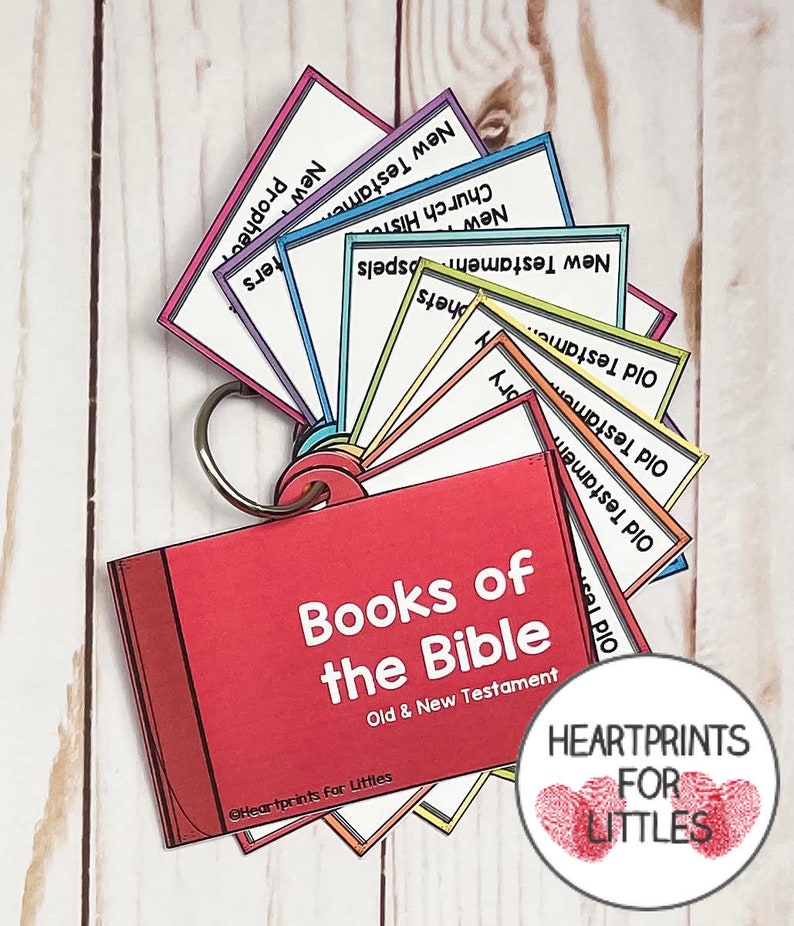 May include: A red book with the title "Books of the Bible" and the subtitle "Old & New Testament". The book is open to reveal a set of colorful cards with the names of the books of the Bible, including "Old Testament", "New Testament", "Prophets", "Gospels", "Church History", and "Letters".