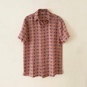 May include: A pink short-sleeved button-down shirt with a floral print in shades of purple, white, and green.