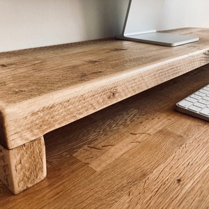 Pu&ograve; includere: Un supporto per monitor in legno rustico con una finitura in legno naturale. Il supporto ha un design semplice con un piano rettangolare e due gambe. Il supporto &egrave; realizzato in legno riciclato e ha un aspetto unico e artigianale.