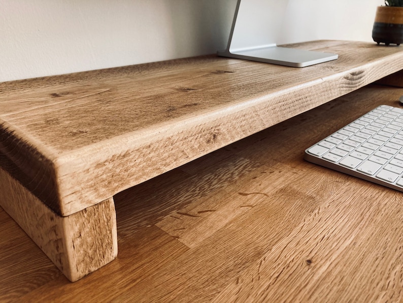 Pu&ograve; includere: Un supporto per monitor in legno rustico con una finitura in legno naturale. Il supporto ha un design semplice con un piano rettangolare e due gambe. Il supporto &egrave; realizzato in legno riciclato e ha un aspetto unico e artigianale.