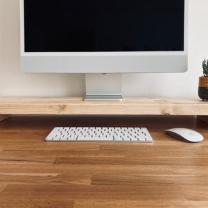 Pu&ograve; includere: Un supporto per monitor in legno con un monitor per computer, una tastiera e un mouse in cima. Il supporto &egrave; realizzato in legno naturale e ha un design semplice.