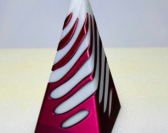 May include: A white and burgundy pyramid-shaped decorative object with a swirling pattern.