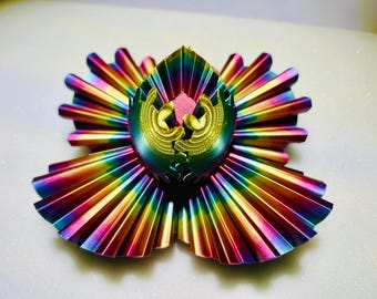 May include: A rainbow iridescent metal sculpture with a geometric design. The sculpture is made of multiple pieces that fit together to create a unique and intricate design.