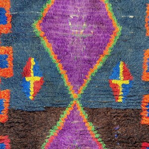 a vibrant, colorful rug with a geometric pattern in shades of purple, blue, orange, and yellow.