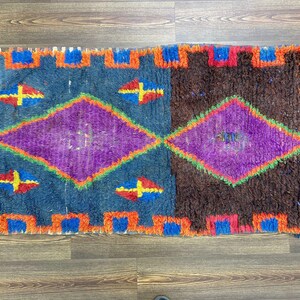 a vibrant, colorful rug with a geometric pattern in shades of blue, purple, and orange.
