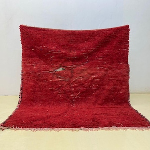 May include: A vibrant red rug with a textured surface and a slightly distressed appearance. The rug has a rectangular shape and a fringe along the bottom edge. The color is a deep, rich red, adding warmth to any space.