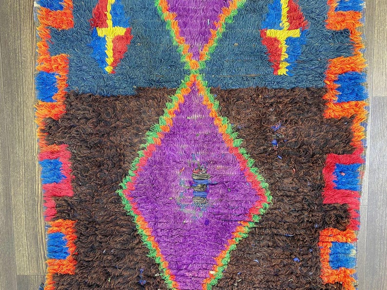 a vibrant, colorful rug with a diamond pattern and a mix of blue, purple, orange, and red hues.