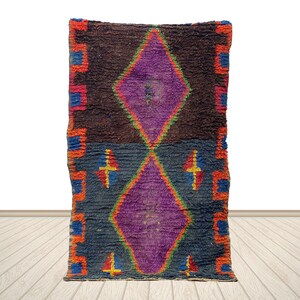 a vibrant, colorful rug with a diamond pattern and geometric shapes in shades of purple, orange, and blue.