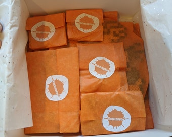 May include: A white box filled with orange tissue paper. Each piece of tissue paper has a Nickelodeon logo with a white splatter design.