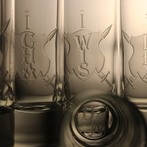 May include: Five clear glass shot glasses with etched designs. Each glass features a shield with a different letter combination: "INT", "CHA", "WIS", "DEX", and "CON".