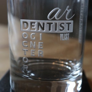 Könnte beinhalten: Ein klares Glas mit den Worten "ar DENTIST" und "OGICNE TER OR", die auf die Seite graviert sind.