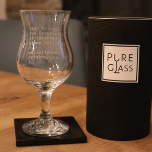 K&ouml;nnte beinhalten: Ein klares Glas mit Stiel und einer breiten Schale, graviert mit einem humorvollen Code-Snippet. Das Glas steht auf einem schwarzen Untersetzer. Das Glas ist in einer schwarzen Box verpackt, auf der "PURE GLASS" steht.