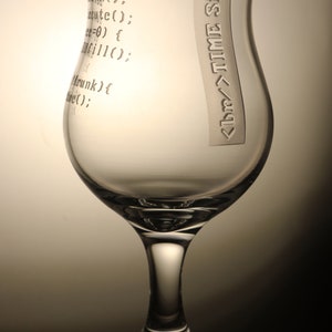 K&ouml;nnte beinhalten: Ein klares Glas mit breiter Basis und schmalem oberen Rand. Das Glas hat den Text "hink(); cute(); e=0) { fillo: Mrunk) { bre();" und "<br/>TIME Simon" auf der Seite eingraviert.