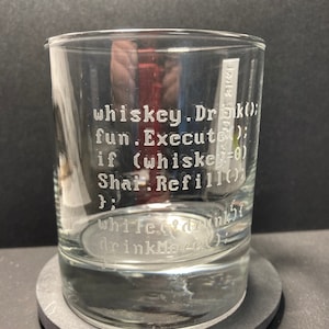 K&ouml;nnte beinhalten: Ein klares Glas mit einem humorvollen Code, der auf die Seite ge&auml;tzt ist. Der Code lautet: "whiskey.Drk(); fun.Execute(); if (whiskey=0) Shar. Refill(); while(drunk) drinkMore();"
