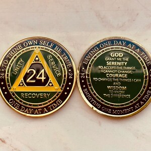 May include: A gold-colored coin with a green and yellow triangle design. The triangle has the words "Unity", "Service", and "Recovery" inscribed on each side. The number "24" is in the center of the triangle. The coin has the text "24 Hours to Thine Own Self Be True" around the edge. The back of the coin has the text "Living One Day at a Time" and a quote about serenity, courage, and wisdom.