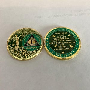 May include: Gold coin with a green background and the words "To thine own self be true" and "One Year" on it. The coin also has a green triangle with the number "1" and the words "Unity Service Recovery" on it.