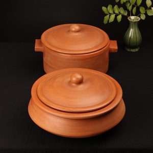 May include: Two terracotta pots with lids. The pots are brown and have a smooth, rounded shape. The lids have a small knob on top.